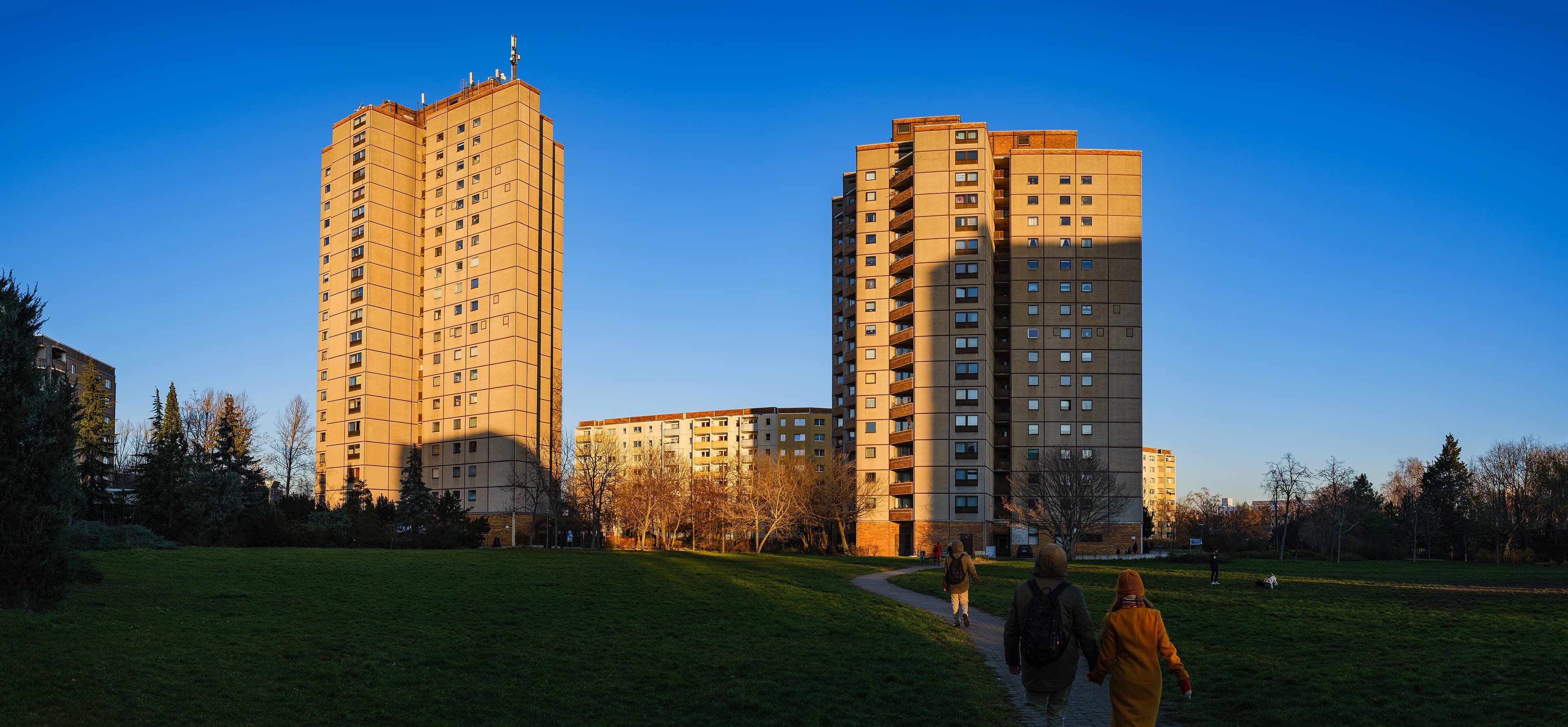 Des immeubles berlinois dans la lumière du soir, deux personnes marchent main dans la main